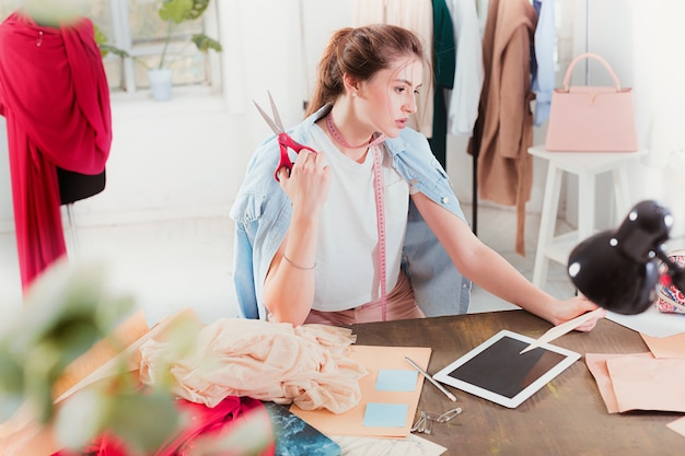 Diseñador de moda mujer trabajando en estudio sentado en el escritorio