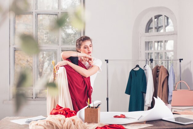 Diseñador de moda mujer trabajando en estudio sentado en el escritorio