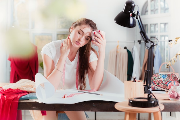 Diseñador de moda trabajando en estudio sentado en el escritorio