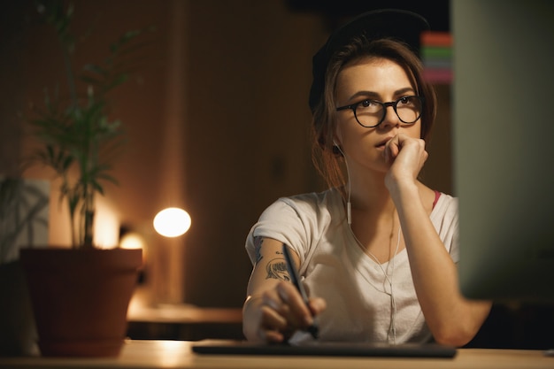 Diseñadora concentrada usando tableta gráfica y computadora]