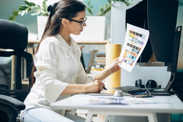 Diseñadora digital femenina mirando muestras en una oficina