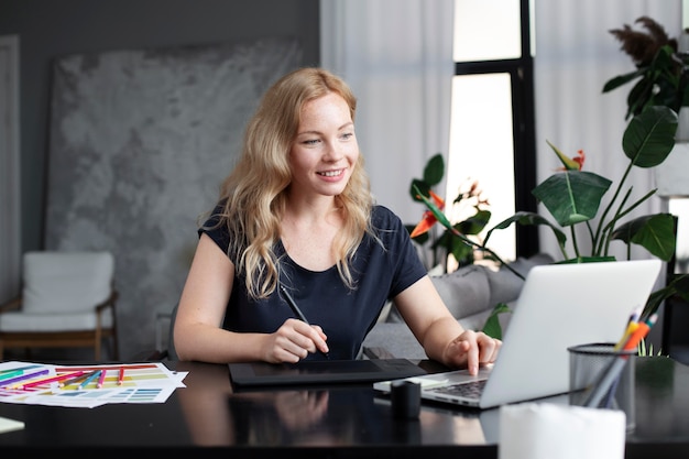 Diseñadora de logotipos trabajando en su tableta conectada a una computadora portátil