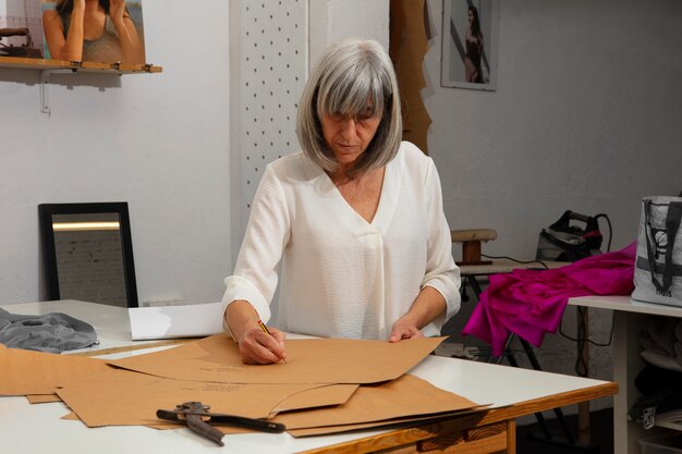 Diseñadora de moda femenina en el estudio trabajando en ropa