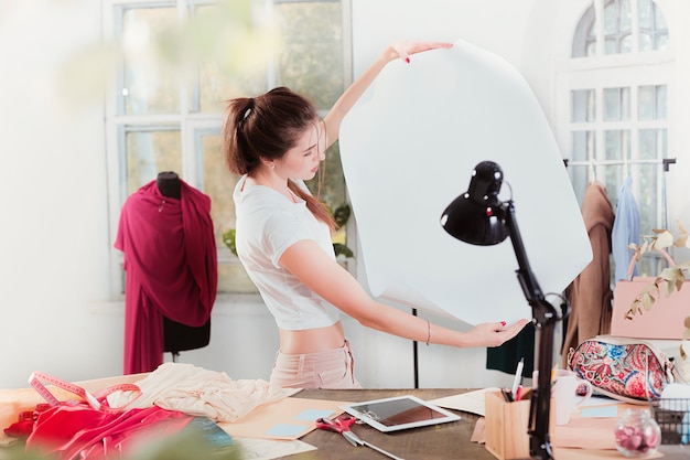 La diseñadora de moda femenina que trabaja en el estudio sentado en el escritorio