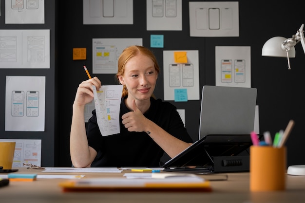 Foto gratuita diseñadora web femenina con papeles y notas en la oficina