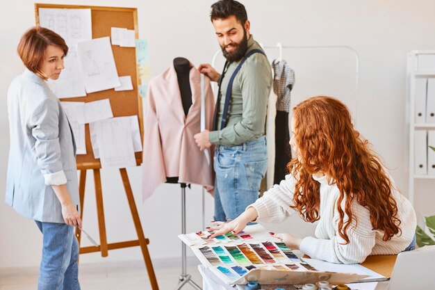 Diseñadores de moda que trabajan en un taller con forma de vestido y paleta de colores.