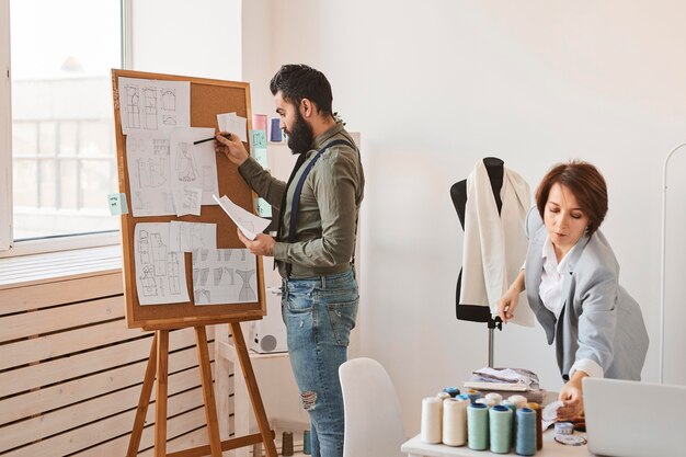 Diseñadores de moda en taller con forma de vestido y tablero de ideas.