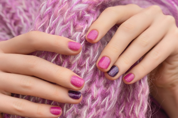 Diseño de uñas rosadas. Cuidados manos femeninas sobre fondo rosa.