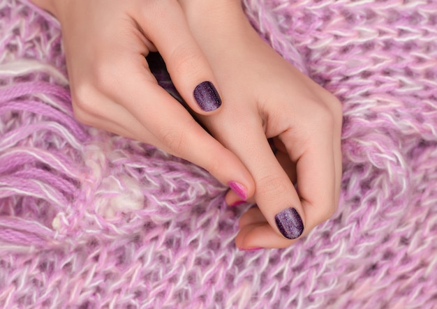 Diseño de uñas rosadas. Cuidados manos femeninas sobre fondo rosa.