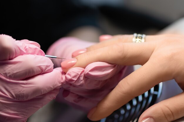 Diseño de uñas rosadas. Mano femenina con manicura brillo.