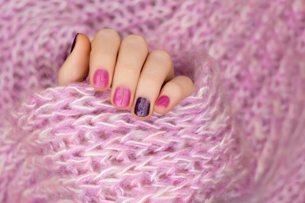 Diseño de uñas rosadas. Mano femenina con manicura brillo.