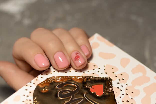 Diseño de uñas rosadas. Mano femenina con manicura rosa.