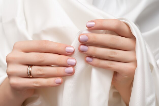 Diseño de uñas rosadas. Manos femeninas con brillo manicura.