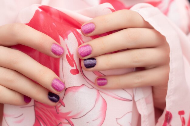 Diseño de uñas rosadas. Manos femeninas con brillo manicura.