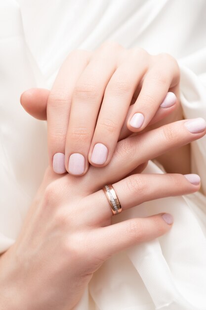 Diseño de uñas rosadas. Manos femeninas con brillo manicura.
