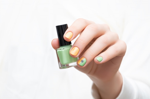 Diseño de uñas verde. Mano femenina con uñas de diente de león.