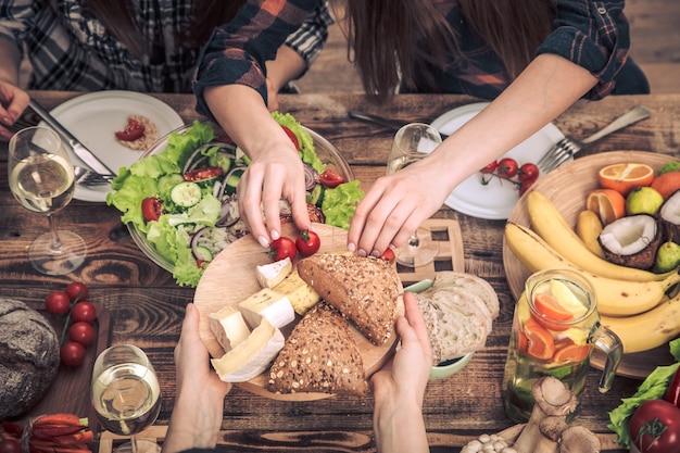 Disfrutando de la cena con mis amigos. Vista superior de un grupo de personas cenando juntas, sentadas en una mesa de madera rústica, el concepto de celebración y comida casera saludable