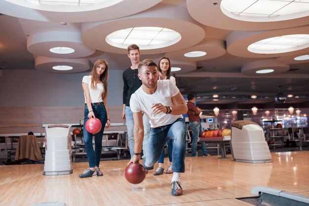 Disfrutando del juego. Jóvenes amigos alegres se divierten en el club de bolos en sus fines de semana