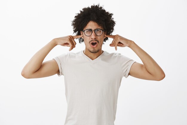 Disgustado hombre discutiendo con gafas cerró los oídos por un ruido horrible