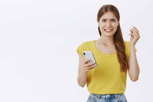 Disgustado y quejándose de la chica de la ginebra que se quita el auricular y hace muecas por la música horrible, sosteniendo el teléfono inteligente