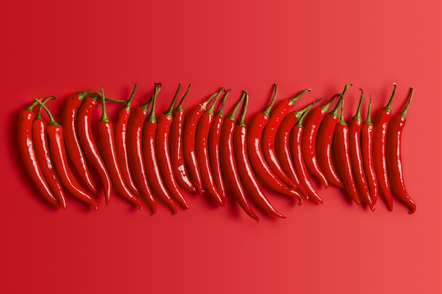 Foto gratuita disparo aislado de chile pimiento rojo picante con tallo verde y piel brillante para condimentar. símbolo de méxico. colección de producto picante. enfoque selectivo. concepto de cocina saludable. vegetales frescos