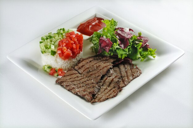 Disparo aislado de filete de ternera con arroz, ensalada y lechuga: perfecto para un blog de comida o uso de menú