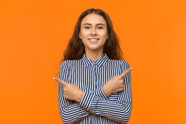 Disparo aislado de hermosa joven alegre vistiendo elegante camisa a rayas sonriendo felizmente