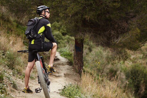 Disparo al aire libre de jóvenes varones europeos vistiendo ropa de ciclismo, casco y gafas