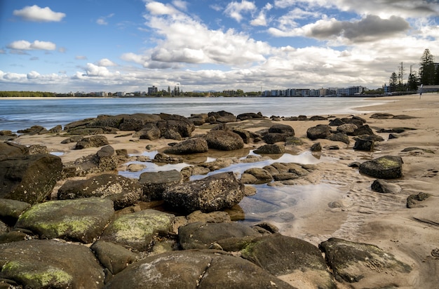 Disparo al nivel de los ojos de piedras en una playa bajo el cielo nublado azul