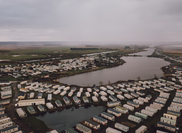 Foto gratuita disparo de alto ángulo de las casas rectangulares en los campos junto a un hermoso estanque de niebla