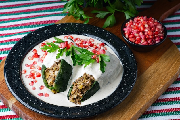 Disparo de alto ángulo de Chiles en nogada en un plato sobre una tabla de madera sobre la mesa