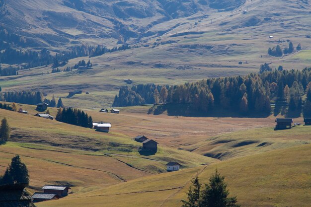 Disparo de alto ángulo de edificios en colinas cubiertas de hierba en Dolomita Italia