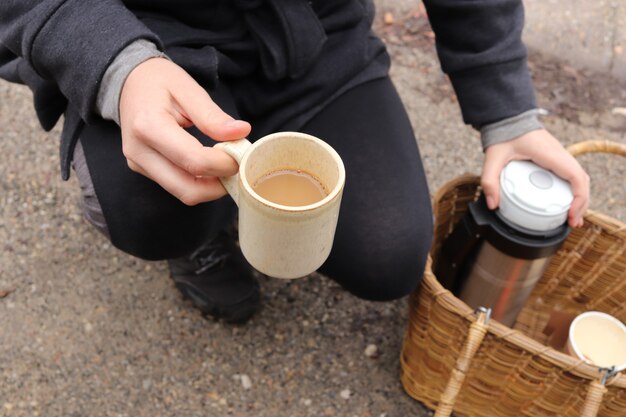 Disparo de alto ángulo de un excursionista sosteniendo una taza de café y un matraz