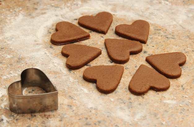 Disparo de alto ángulo de galletas en forma de corazón junto a un cortador de galletas en forma de corazón