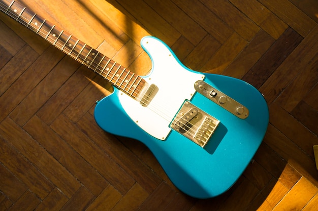 Foto gratuita disparo de alto ángulo de una guitarra azul sobre una superficie de madera