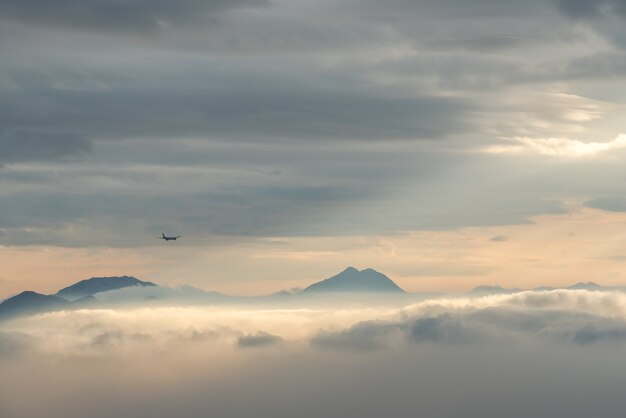 Disparo de alto ángulo de las hermosas cimas de las montañas visibles a través de las nubes y la niebla