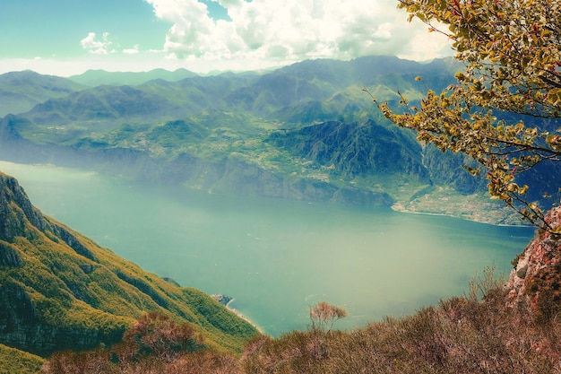 Disparo de alto ángulo de un lago rodeado de verdes montañas cubiertas de niebla bajo el cielo nublado