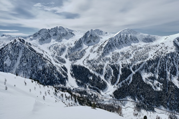 Disparo de alto ángulo de una montaña boscosa cubierta de nieve en el Col de la Lombarde - Isola