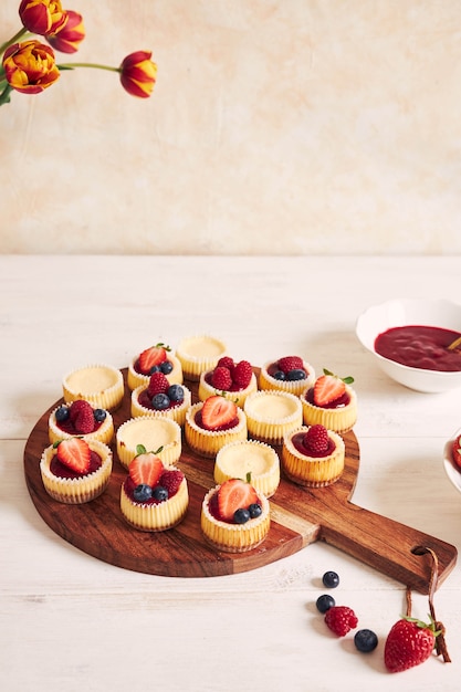 Disparo de alto ángulo de pastelitos de queso con mermelada de frutas y frutas en una placa de madera