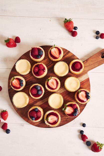 Disparo de alto ángulo de pastelitos de queso con mermelada de frutas y frutas en una placa de madera