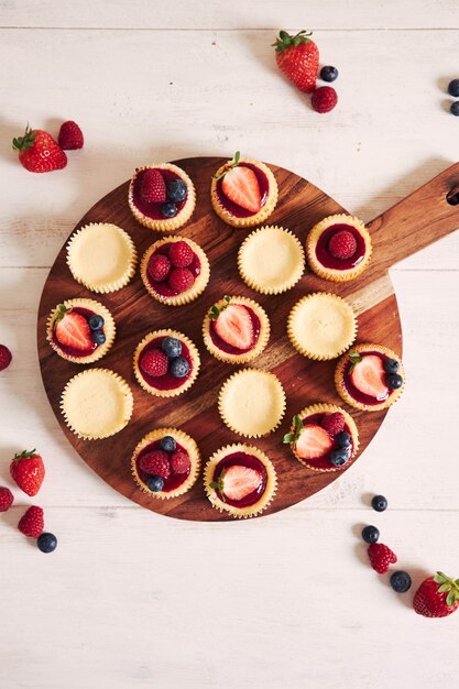 Disparo de alto ángulo de pastelitos de queso con mermelada de frutas y frutas en una placa de madera