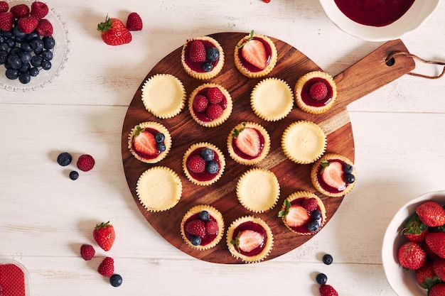 Disparo de alto ángulo de pastelitos de queso con mermelada de frutas y frutas en una placa de madera