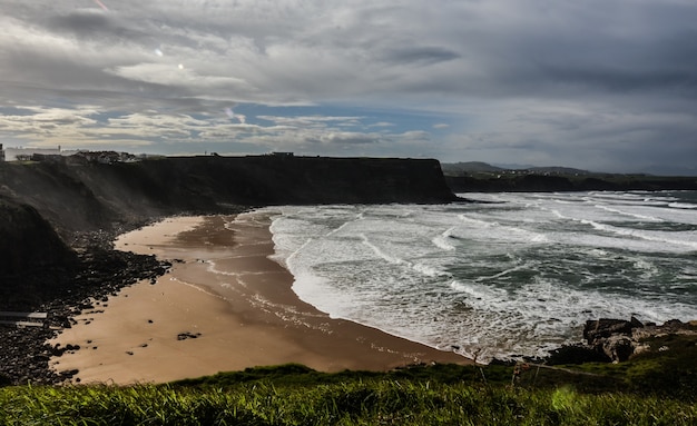 Disparo de alto ángulo de una playa rocosa rodeada de acantilados bajo un cielo nublado