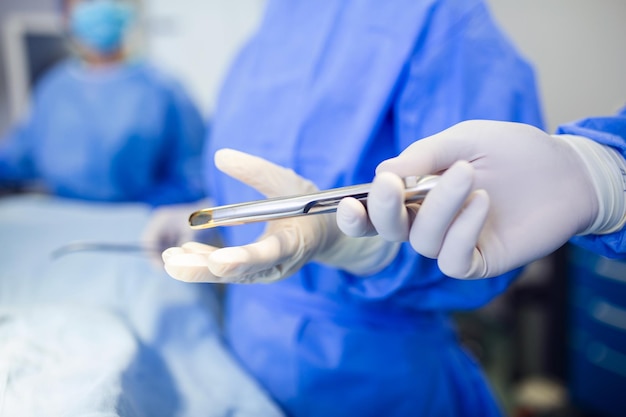 Disparo de ángulo bajo en el asistente de quirófano entrega instrumentos a los cirujanos durante la operación Los cirujanos realizan la operación Médicos profesionales que realizan la cirugía