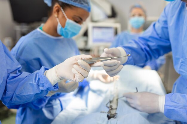 Disparo de ángulo bajo en el asistente de quirófano entrega instrumentos a los cirujanos durante la operación Los cirujanos realizan la operación Médicos profesionales que realizan la cirugía
