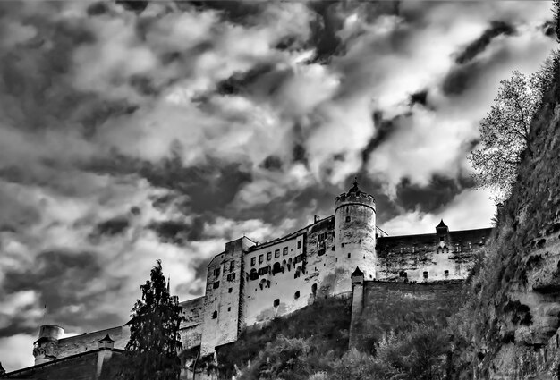 Disparo de ángulo bajo en escala de grises del castillo de Hohensalzburg contra un cielo nublado en Salzburgo, Austria