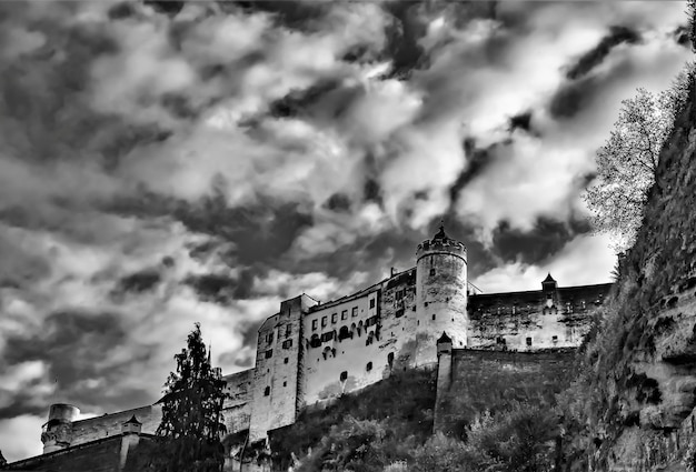 Disparo de ángulo bajo en escala de grises del castillo de Hohensalzburg contra un cielo nublado en Salzburgo, Austria