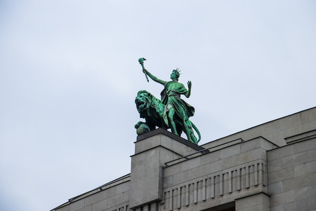 Disparo de ángulo bajo la estatua del león en el Banco Nacional de la República Checa bajo un cielo nublado