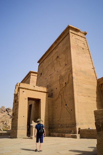Disparo de ángulo bajo de un hombre de pie delante del templo de Isis Asuán en Egipto