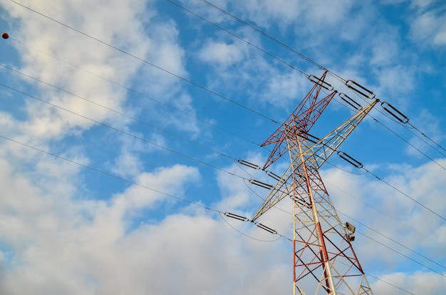 Disparo de ángulo bajo de una torre de alta transmisión con un nublado cielo azul en el